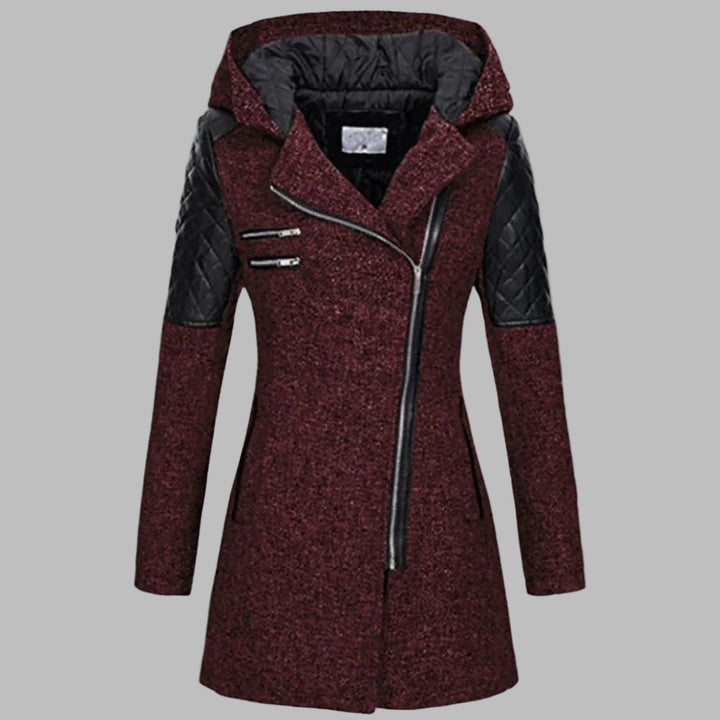 Donkerrode dames winterjas met capuchon, asymmetrische rits en zwarte leren accenten. Stijlvolle en warme jas voor koude winterdagen.